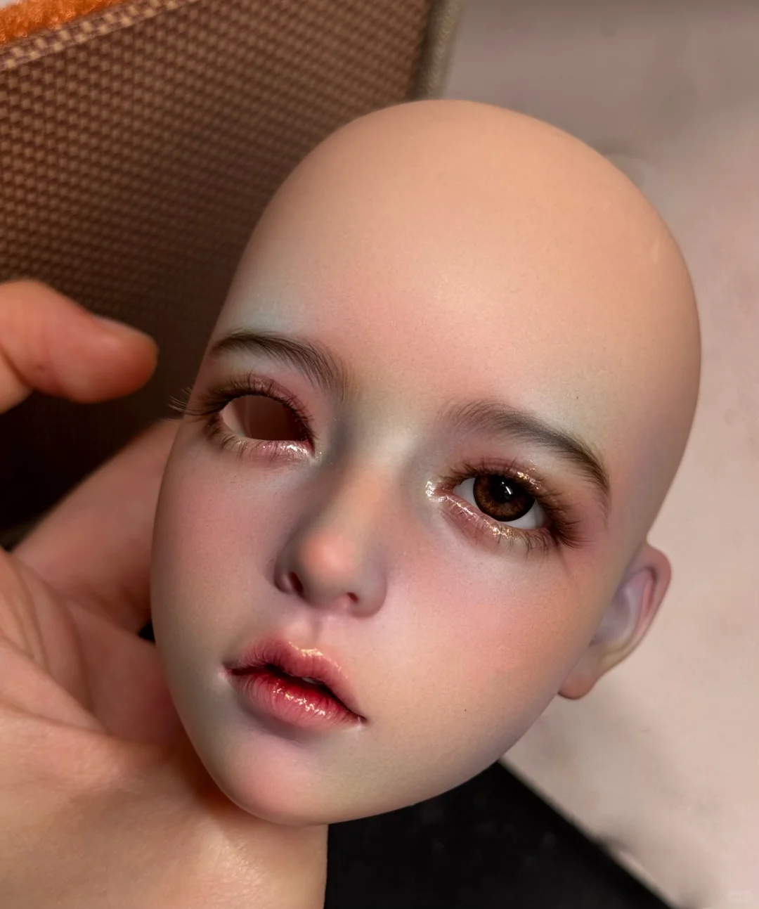 Close-up BJD head showing a soft natural faceup with one eye installed
